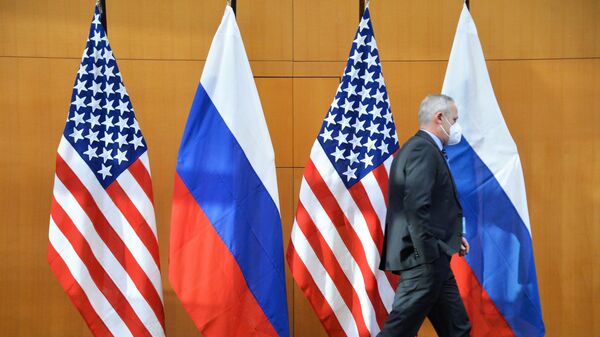 Мужчина проходит мимо флагов во время двусторонних переговоров по безопасности между США и Россией в Женеве. - Sputnik Армения