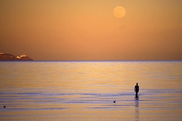 Мужчина на пляже во время полнолуния в Ирландии. - Sputnik Армения