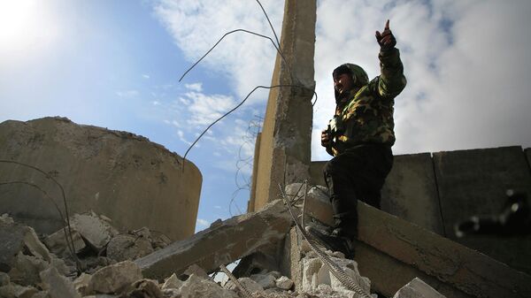 Боец Сирийских демократических сил под руководством курдов стоит у разрушенной части оборонительной стены тюрьмы Гвейран в Хасаке (23 января 2022). Сирия - Sputnik Армения