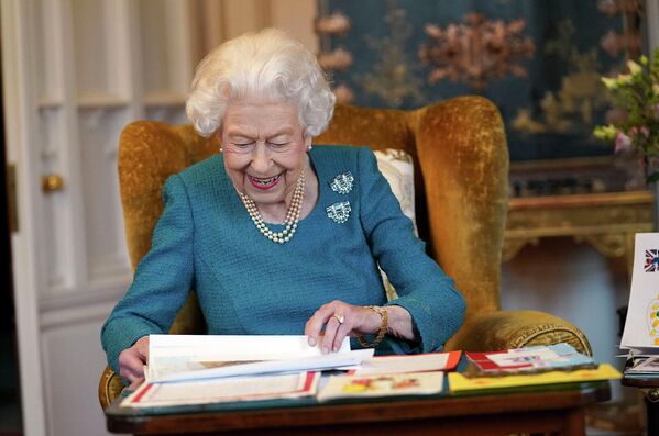 Королева Великобритании Елизавета II рассматривает фотографии памятных вещей с ее Золотого и Платинового юбилеев в Дубовой комнате в Виндзорском замке (4 февраля 2022). Англия.  - Sputnik Армения