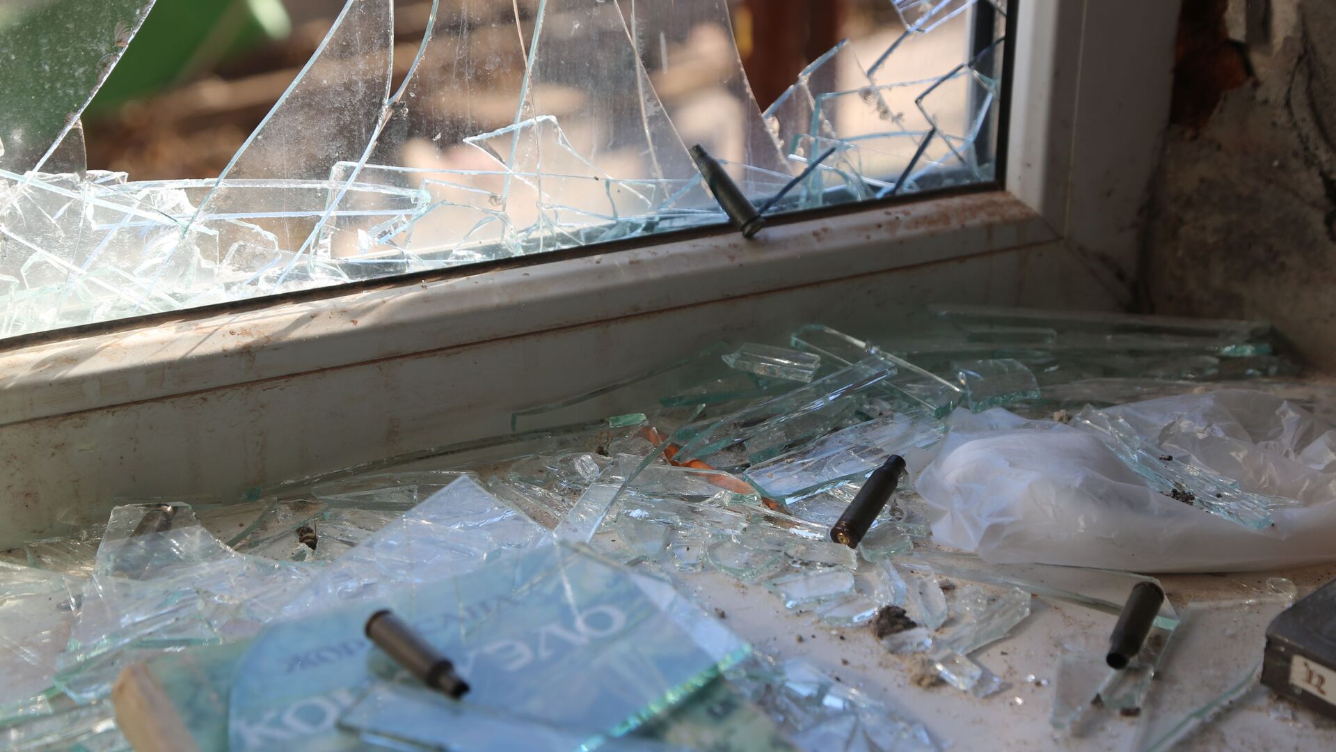 Разбитое окно и гильзы на подоконнике в жилом доме в Киевском районе Донецка - Sputnik Армения, 1920, 23.02.2022