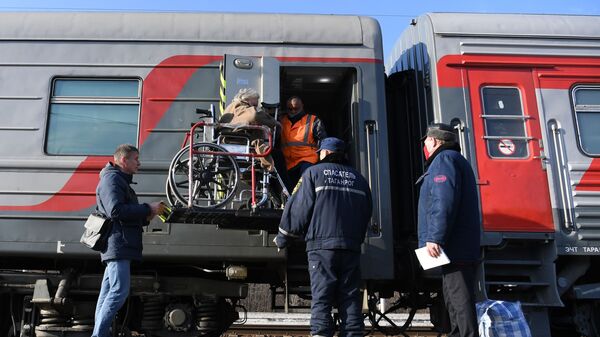 Сотрудники МЧС и РЖД помогают женщине сесть в поезд на железнодорожном вокзале Таганрог-1 в Ростовской области - Sputnik Армения