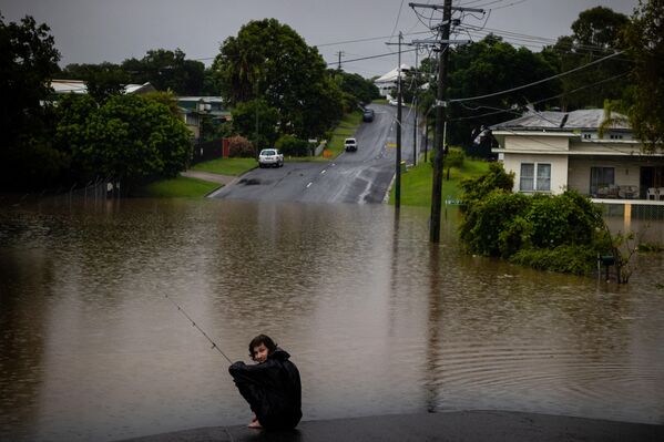 Житель города Вест-Испвич в Австралии Джай Коннорс ловит рыбу в паводковой воде перед своим домом. - Sputnik Армения