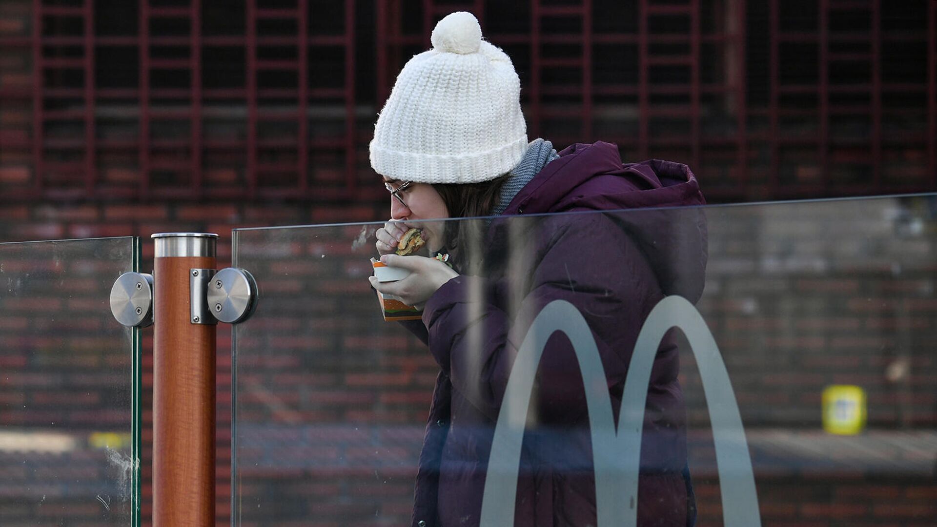 Девушка ест гамбургер у ресторана Макдоналдс (9 марта 2022). Москвa - Sputnik Армения, 1920, 19.05.2022