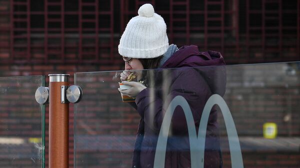 Девушка ест гамбургер у ресторана Макдоналдс (9 марта 2022). Москвa - Sputnik Армения