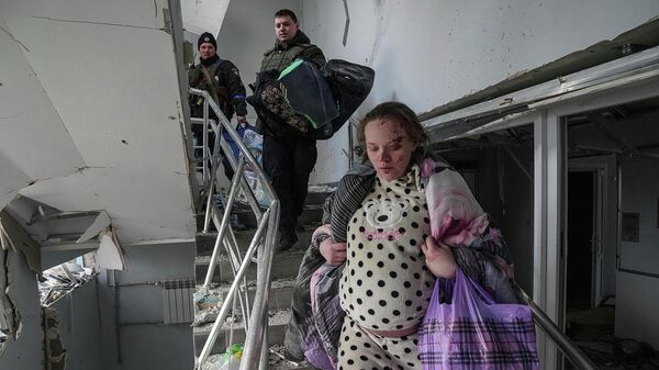 Раненая беременная женщина спускается по лестнице в родильном доме, пострадавшем от обстрела (9 марта 2022). Мариуполь - Sputnik Армения