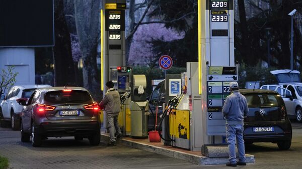 Работник меняет цены на топливо на табло на заправочной станции в Милане - Sputnik Армения
