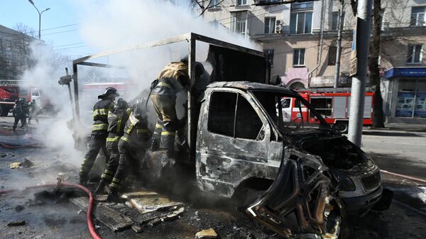 Сотрудники пожарной охраны у разрушенной машины в результате взрыва в центре Донецка - Sputnik Армения