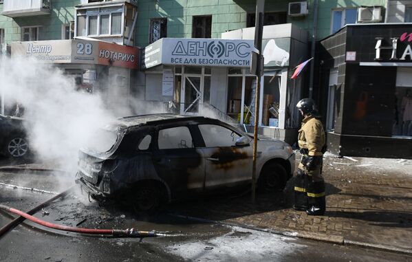 Сотрудник пожарной охраны у разрушенной машины в результате взрыва в центре Донецка.  - Sputnik Армения