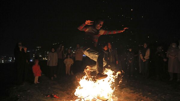 Мужчина прыгает через костер на празднике огня Чахаршанбе-Сури в Тегеране  - Sputnik Армения