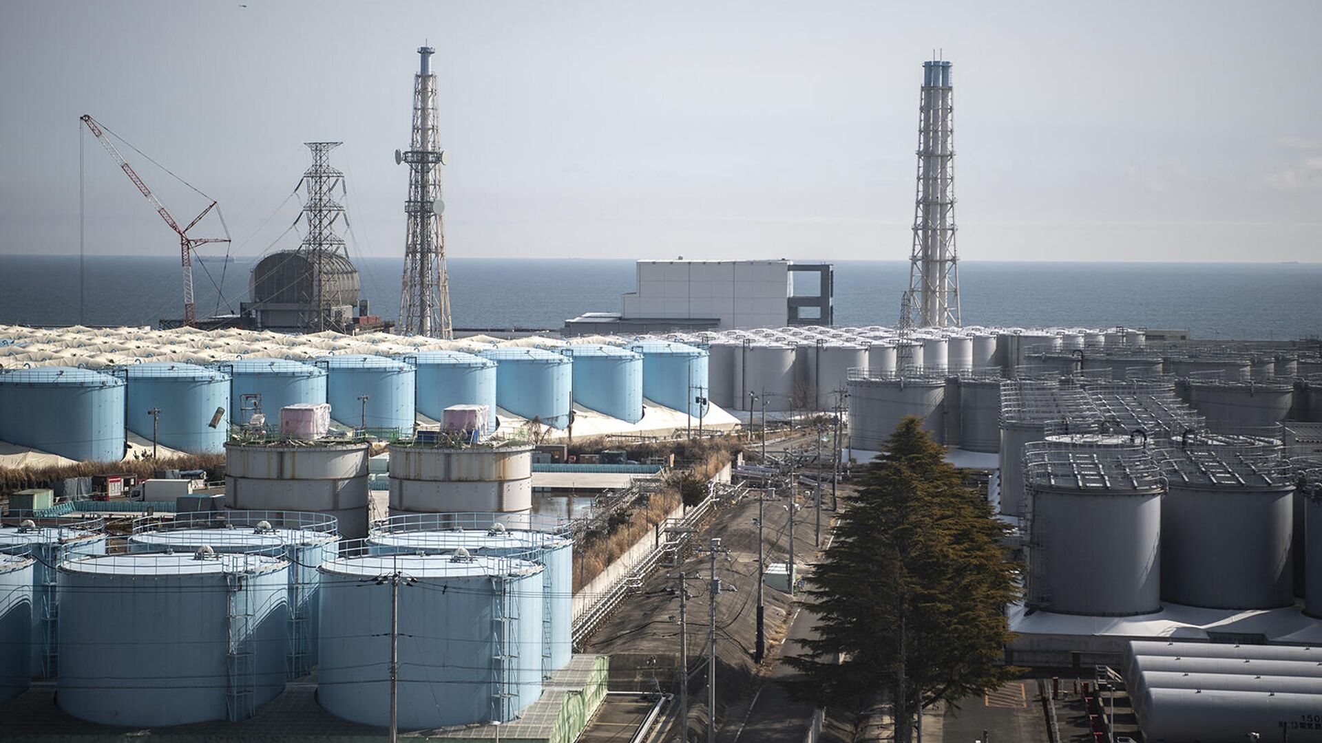 Здания реакторов энергоблоков 3 (слева) и 4 (в центре) и резервуары для хранения загрязненной воды на АЭС Фукусима Дай-ичи - Sputnik Армения, 1920, 16.03.2022