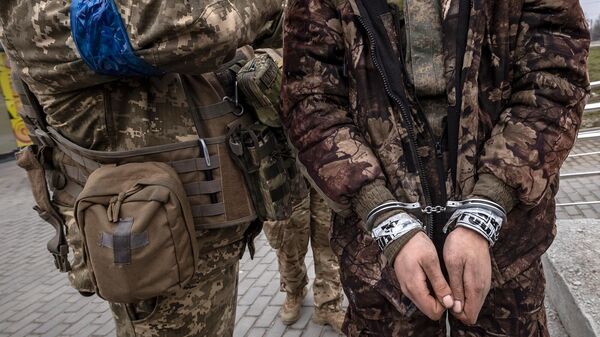 Украинский военнослужащий стоит рядом с закованным в наручники российским солдатом (31 марта 2022). Харьков - Sputnik Армения