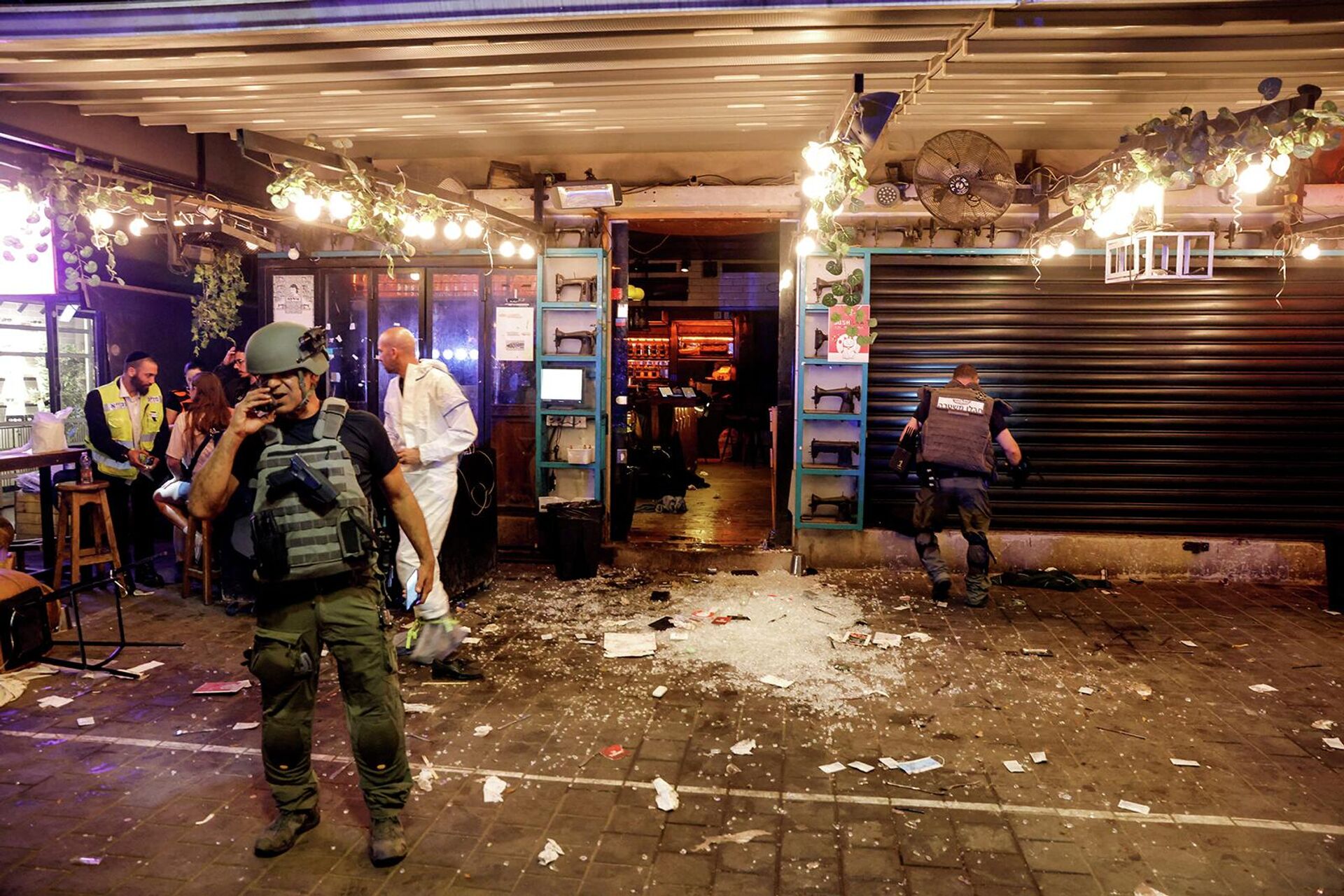 Израильские службы безопасности и спасатели работают у входа в ресторан после инцидента со стрельбой (8 апреля 2022). Тель-Авив - Sputnik Армения, 1920, 08.04.2022