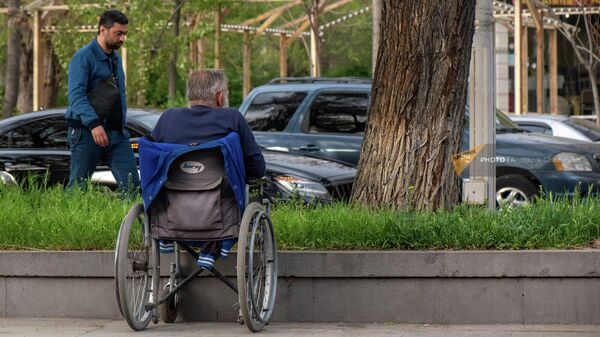 Мужчина в инвалидной коляске смотрит на проезжающие автомобили - Sputnik Армения