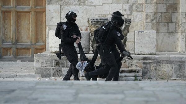 Израильская полиция несет палестинского протестующего во время столкновений у комплекса мечети Аль-Акса (22 апреля 2022). Иерусалим - Sputnik Армения
