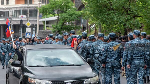 Автомобиль с флагами Армении и Арцаха проезжает мимо сопровождающих шествие сотрудников полиции на улице Сарьяна (3 мая 2022). Еревaн - Sputnik Армения