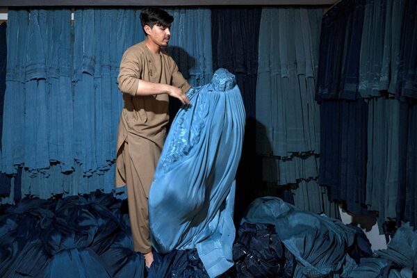 Афганский продавец демонстрирует паранджу в своем магазине на рынке Мандави в Кабуле - Sputnik Армения