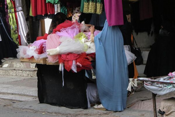 Женщина в парандже выбирает детскую одежду в магазине в Герате - Sputnik Армения