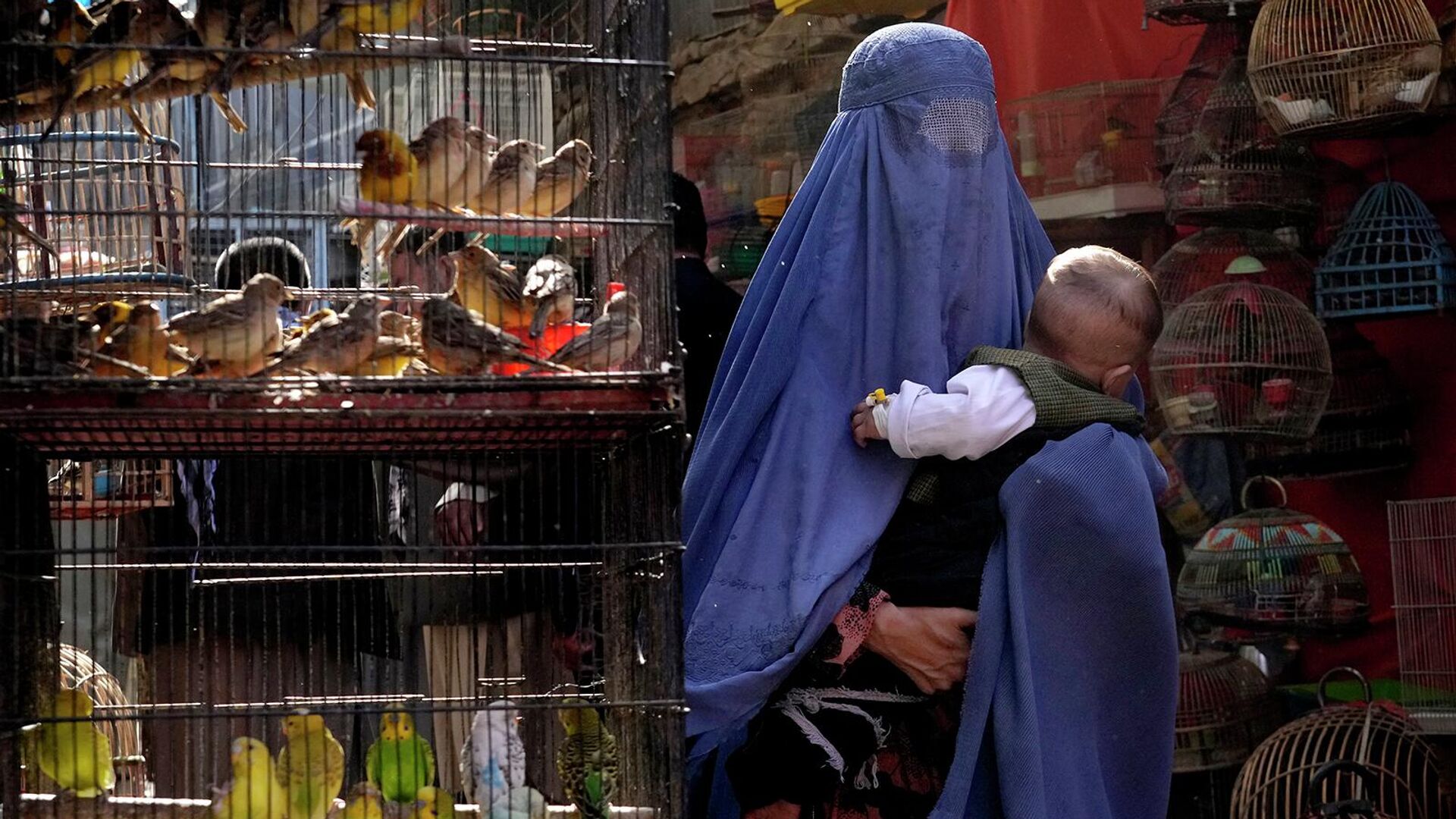 Женщина в парандже с ребенком на руках на птичьем рынке в Кабуле (8 мая 2022). Афганистан - Sputnik Армения, 1920, 04.09.2022