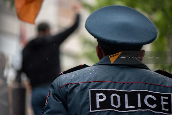 Сотрудник полиции наблюдает за выступлением Артура Казиняна перед зданием генпрокуратуры (12 мая 2022). Еревaн - Sputnik Армения