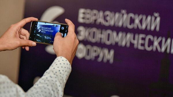 Посетитель фотографирует баннер Евразийского экономического форума (26 мая 2022). Бишкек - Sputnik Армения