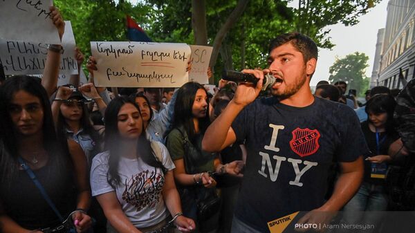 Молодежь с защелкнутыми наручниками на руках и черными повязками на губах проводит акцию протеста у здания Генпрокуратуры (11 июня 2022). Еревaн - Sputnik Армения