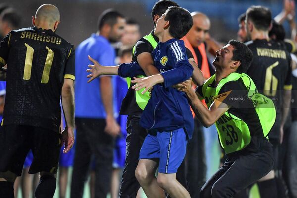 Стюарды задерживают болельщика, выбежавшего на поле по окончании товарищеского матча ветеранов по футболу между сборными Армении и Грузии  - Sputnik Армения