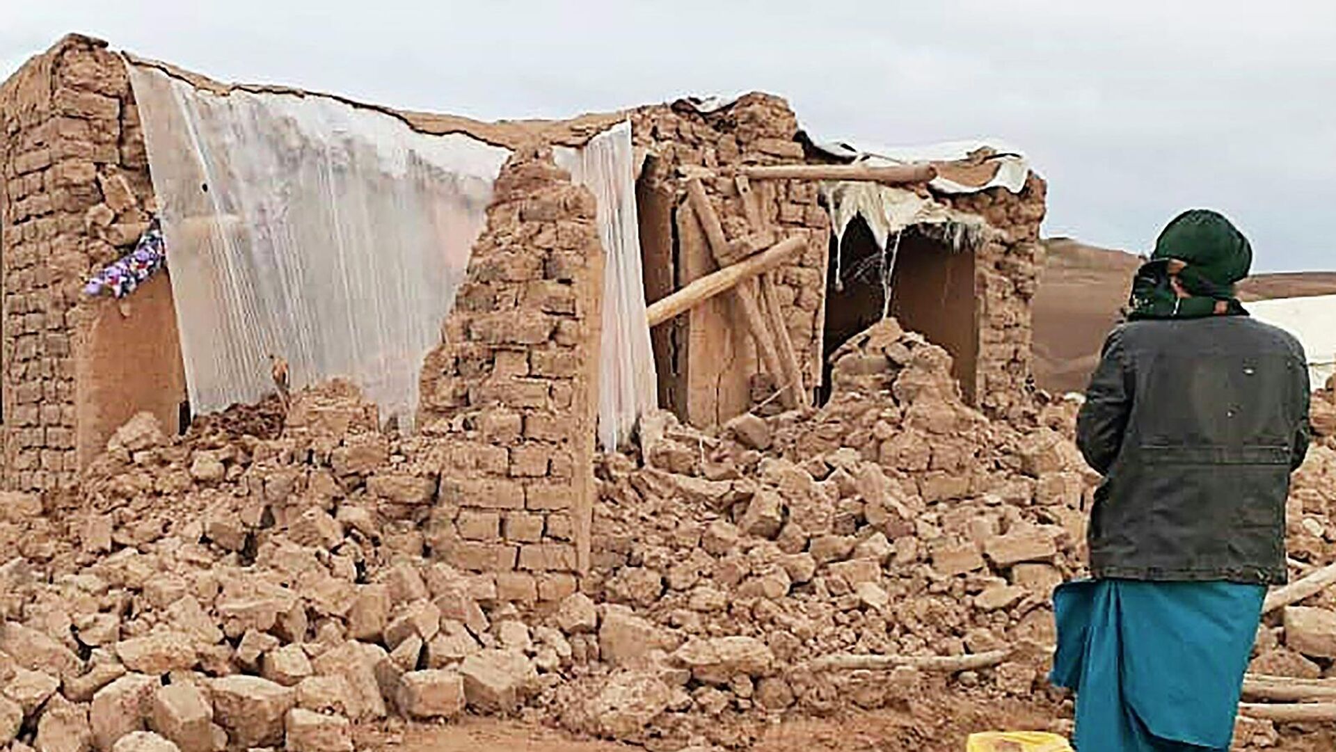 Житель стоит возле разрушенного землетрясением дома в районе Кадис в южной части провинции Бадгис (18 января 2018). Афганистан - Sputnik Армения, 1920, 22.06.2022