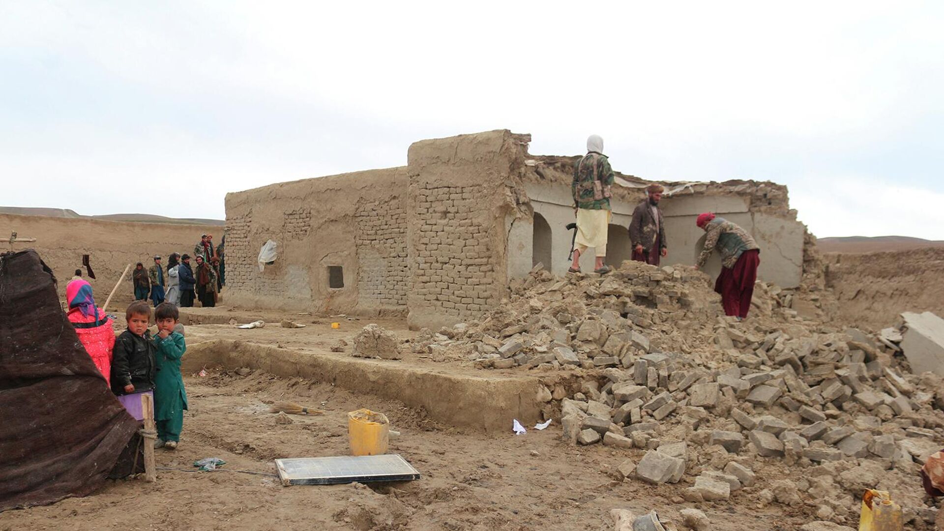 Жители возле разрушенного землетрясением дома в районе Кадис в южной части провинции Бадгис (18 января 2018). Афганистан - Sputnik Армения, 1920, 29.06.2022