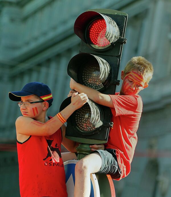 Двое детей держатся за светофорный столб в ожидании прибытия сборной Испании по футболу. - Sputnik Армения