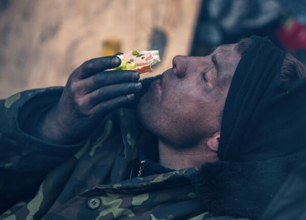 Участник акции оппозиции ест бутерброд на баррикаде на улице Грушевского в Киеве - Sputnik Армения