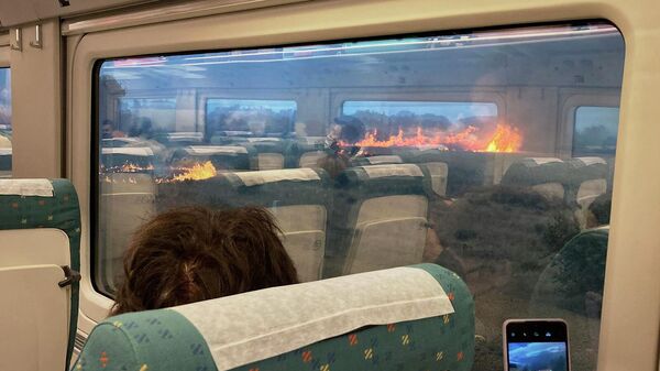 Пассажиры поезда смотрят из окон на лесной пожар в Саморе (18 июля 2022). Испания - Sputnik Армения