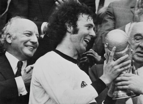 Капитан сборной ФРГ Франц Беккенбауэр держит трофей после победы своей команды над Голландией в ходе ЧМ на Олимпийском стадионе в Мюнхене, 7 июля 1974 года. - Sputnik Армения