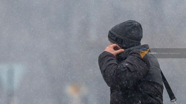 Мужчина идет по площади Республики в снежную погоду - Sputnik Армения