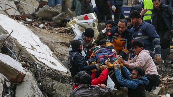 Граждане и аварийные бригады спасают человека на носилках из рухнувшего здания в Адане (6 февраля 2023). Турция - Sputnik Армения