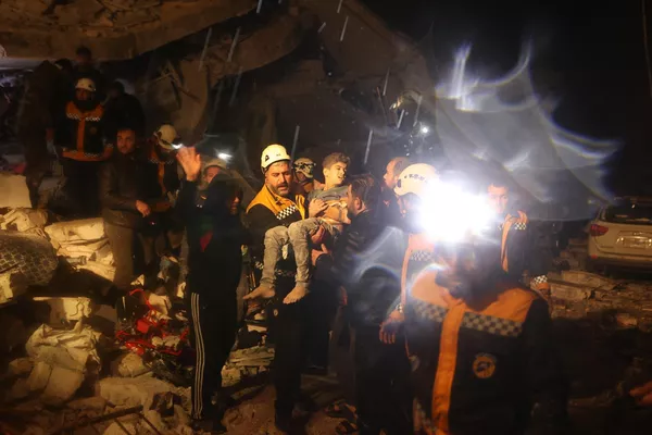Спасатели несут мальчика, извлеченного из-под завалов рухнувшего здания после землетрясения в Дане, Сирия - Sputnik Армения