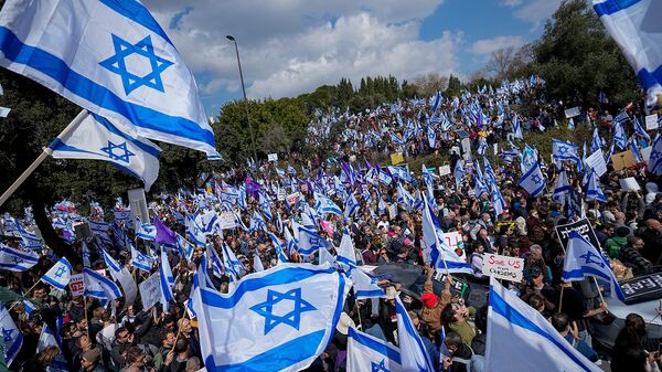 Активисты размахивают флагами Израиля во время протеста против планов нового правительства премьер-министра Биньямина Нетаньяху по реформированию судебной системы у здания Кнессета (13 февраля 2023). Иерусалим - Sputnik Армения