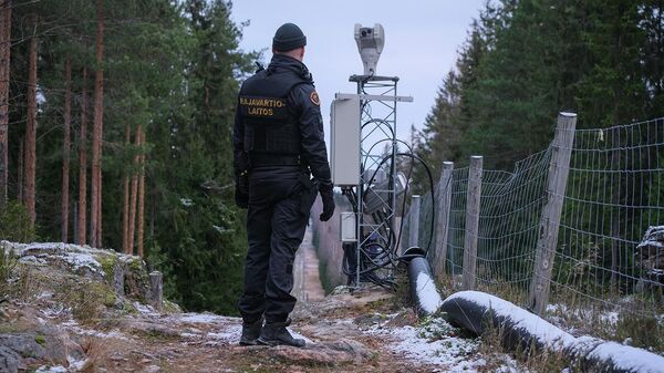 Офицер пограничной службы Финляндии стоит вдоль забора, обозначающего границу между Финляндией и Российской Федерацией, недалеко от пограничного перехода Пелкола (18 ноября 2022). Иматра - Sputnik Армения