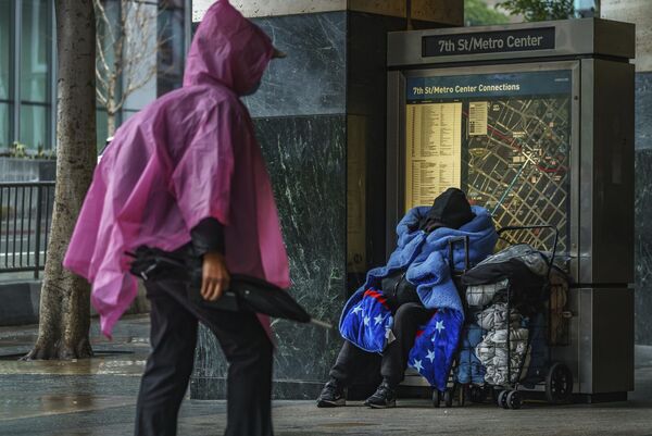 Бездомный укрывается одеялом у входа на станцию метро 7th Street/Metro Center в центре Лос-Анджелеса - Sputnik Армения