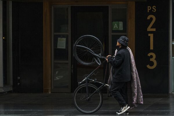 Мужчина идет по тротуару в поисках укрытия от дождя в центре Лос-Анджелеса - Sputnik Армения