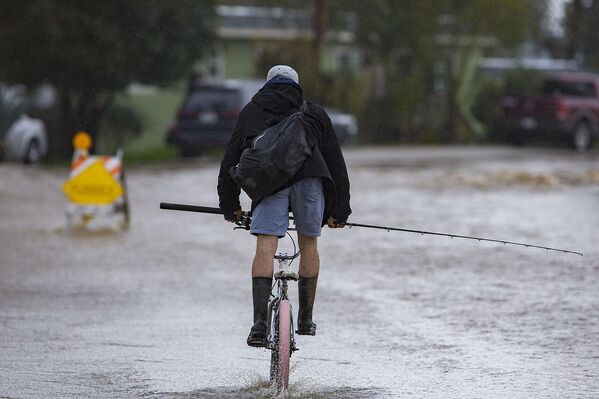 Мужчина едет на велосипеде через паводковые воды на Колледж-роуд в Уотсонвилле  - Sputnik Армения
