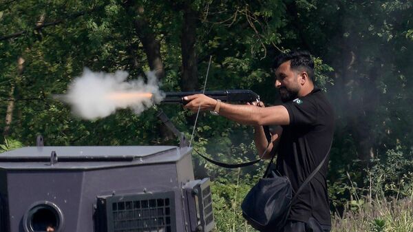 Офицер полиции стреляет из винтовки во время столкновений со сторонниками бывшего премьер-министра Пакистана Имрана Хана (10 мая 2023). Исламабад - Sputnik Армения