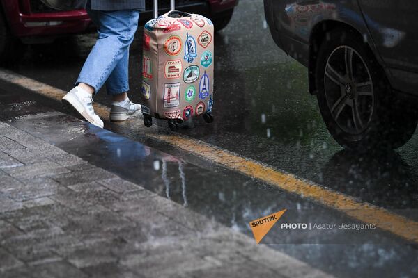 Женщина с чемоданом под дождем на одной улиц в Ереване - Sputnik Армения