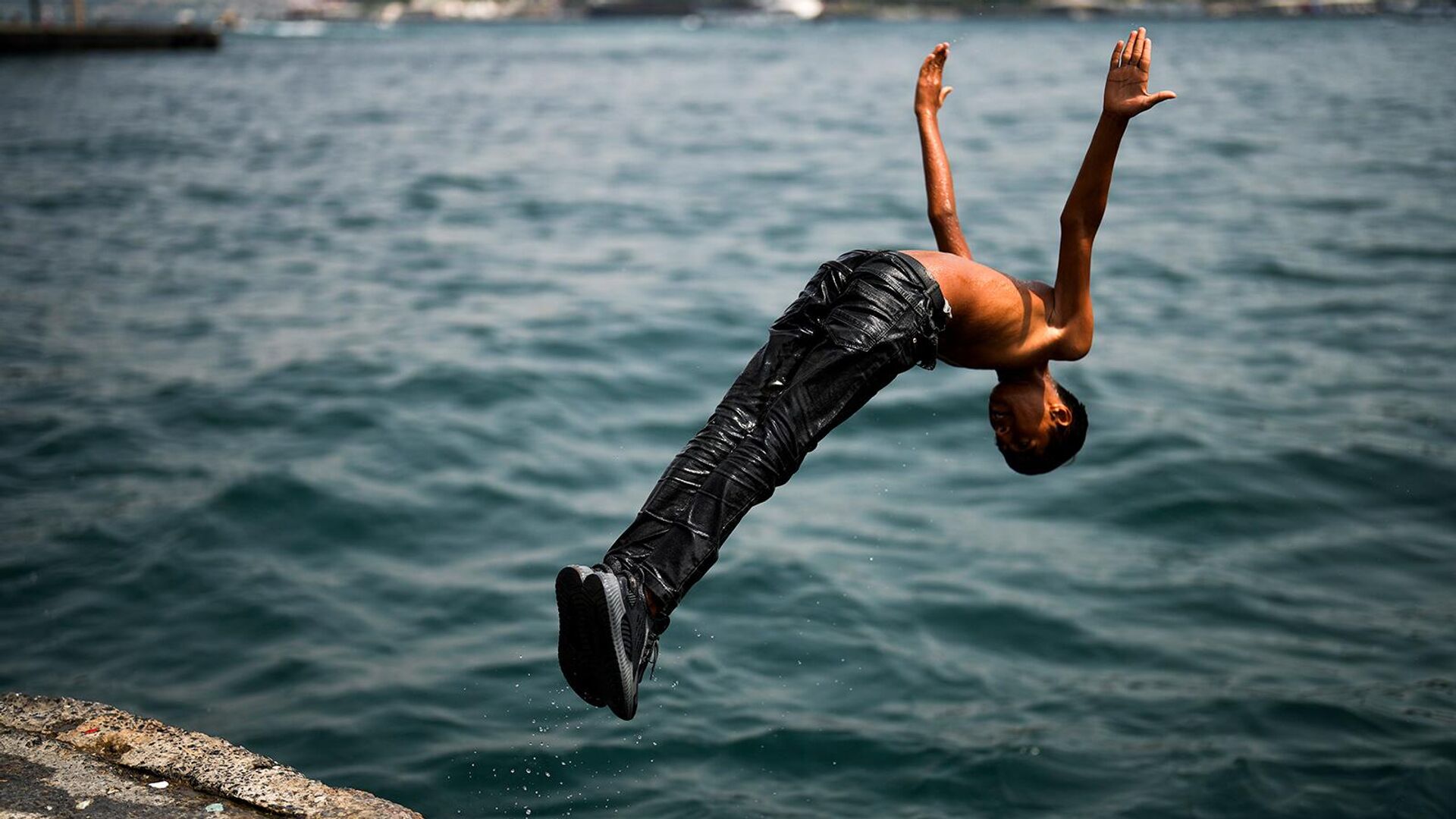 Юноша ныряет в Босфор на набережной Каракой жарким летним днем (14 июля 2023). Стамбул - Sputnik Армения, 1920, 24.07.2023