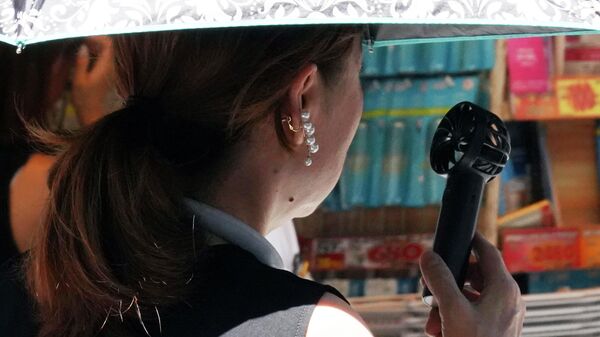 Девушка охлаждается с помощью переносного вентилятора на улице в Токио - Sputnik Армения