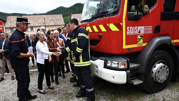Премьер-министр Франции Элизабет Борн пожимает руку пожарному, участвующему в спасательных операциях после пожара в доме отдыха для инвалидов в Винценхайме (9 августа 2023). Франция - Sputnik Армения
