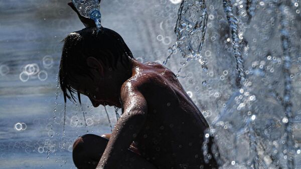 Мальчик поливает себя водой из фонтана на Крымской набережной во время аномальной жары (7 августа 2023). Москва - Sputnik Армения