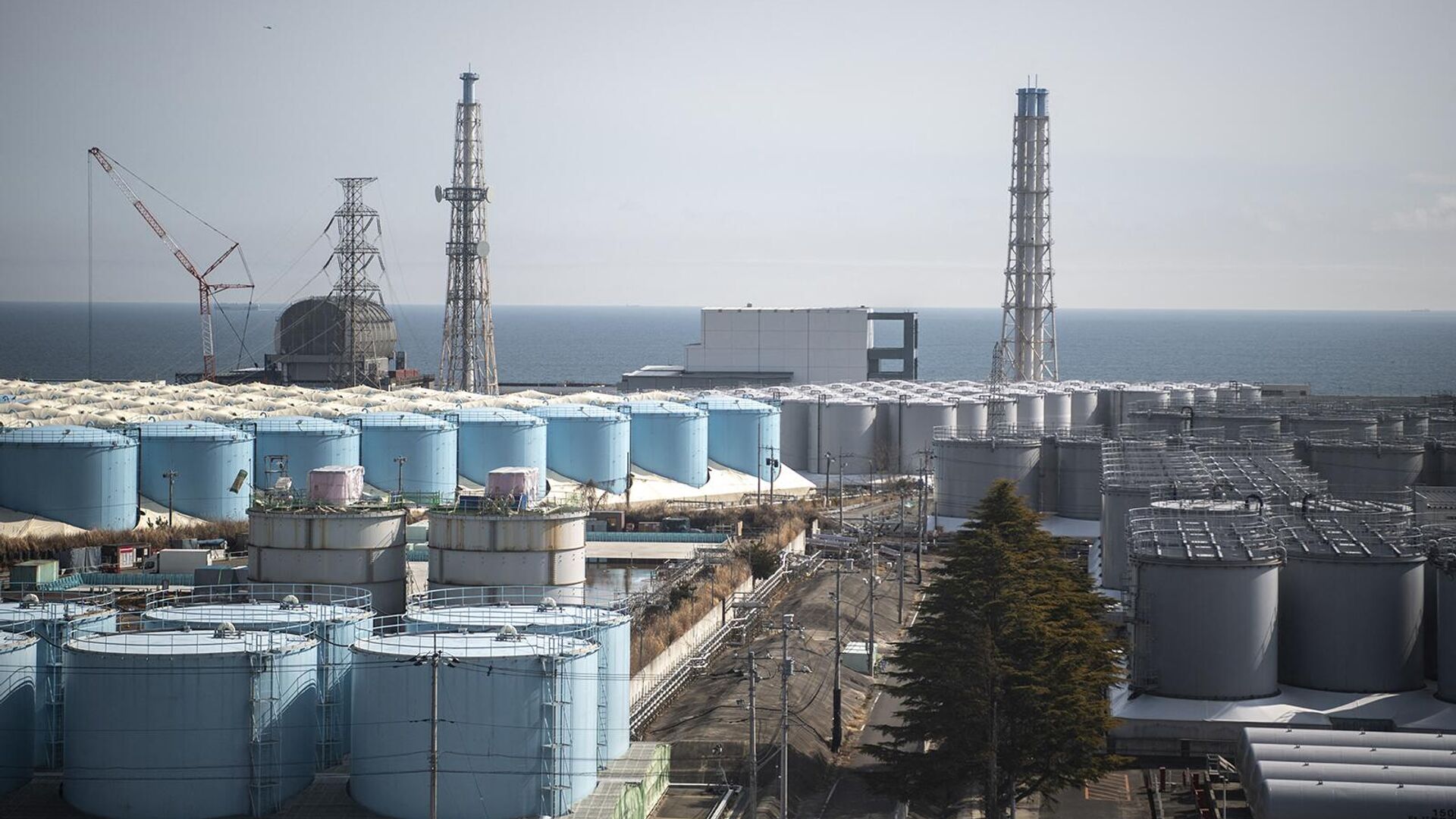 Здания реакторов энергоблоков 3 (слева) и 4 (в центре) и резервуары для хранения загрязненной воды на АЭС Фукусима Дай-ичи - Sputnik Армения, 1920, 28.08.2023