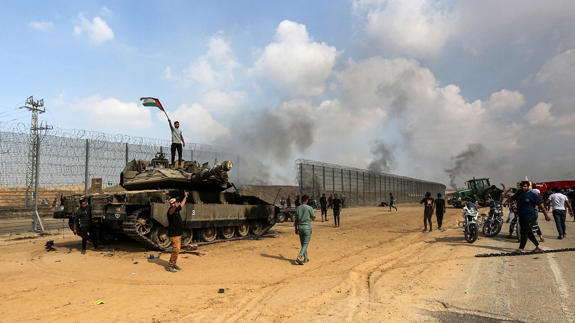 Палестинцы размахивают своим национальным флагом и празднуют у уничтоженного израильского танка у ограждения сектора Газа (7 октября 2023). Хан-Юнис - Sputnik Армения, 1920, 27.10.2023
