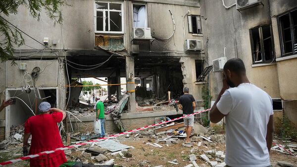 Местные жители осматривают поврежденное жилое здание после попадания в него ракеты, выпущенной из сектора Газа (9 октября 2023). Ашкелон - Sputnik Армения